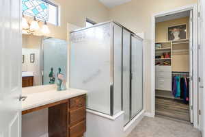 Bathroom featuring tile patterned flooring, a chandelier, walk in shower, and vanity