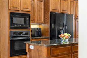 Kitchen featuring black appliances and dark stone countertops