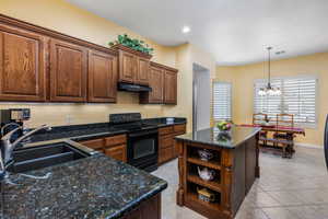 Kitchen featuring a kitchen island, electric range, light tile patterned flooring, and sink