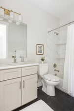 Full bathroom featuring toilet, shower / bath combo with shower curtain, tile patterned floors, and vanity