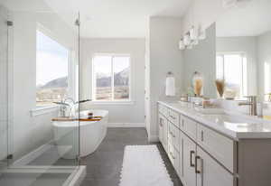 Bathroom featuring a healthy amount of sunlight, a washtub, vanity, and a mountain view