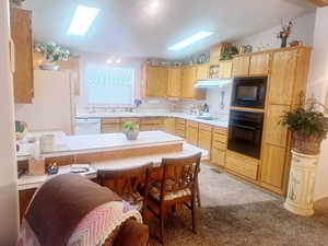 Kitchen with lofted ceiling, kitchen peninsula, black appliances, and light brown cabinets