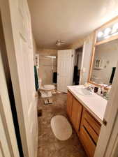 Bathroom featuring toilet, a textured ceiling, a shower with shower door, and vanity