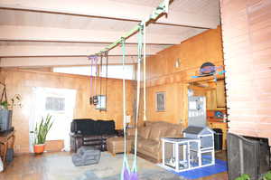 Living room featuring vaulted ceiling with beams, dark hardwood / wood-style flooring, and wood walls