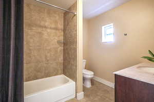 Full bathroom with toilet, tiled shower / bath, tile patterned floors, and vanity