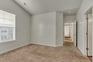 Carpeted empty room with vaulted ceiling