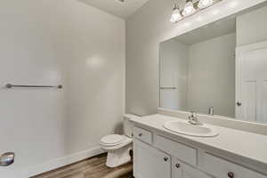 Bathroom featuring wood-type flooring, vanity, and toilet