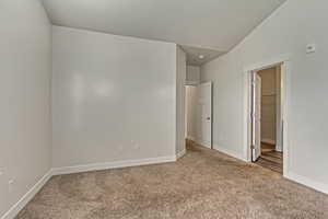 Carpeted empty room featuring vaulted ceiling