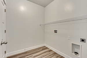 Washroom with electric dryer hookup, washer hookup, and hardwood / wood-style flooring