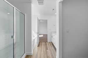 Bathroom with vanity, hardwood / wood-style flooring, and plus walk in shower