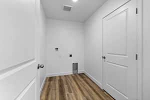 Clothes washing area with washer hookup, dark wood-type flooring, and hookup for an electric dryer