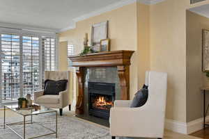 Sitting room with a tiled fireplace, wood-type flooring, a textured ceiling, and ornamental molding