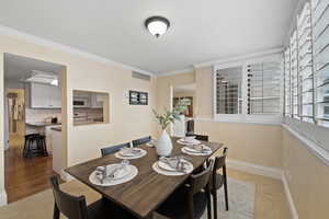 Dining space with light tile patterned flooring and ornamental molding