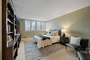 Bedroom with light colored carpet and a textured ceiling