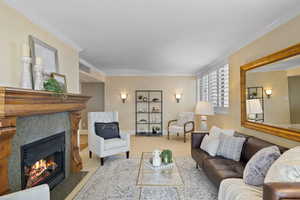 Living room featuring a tiled fireplace, light colored carpet, and ornamental molding