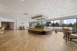 Living room with ornate columns, a textured ceiling, and light wood-type flooring