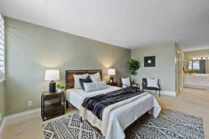 Bedroom featuring ensuite bathroom and light carpet