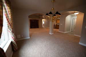 Unfurnished dining area with vaulted ceiling, light carpet, and ceiling fan with notable chandelier