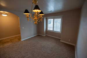 Spare room featuring carpet flooring and a notable chandelier