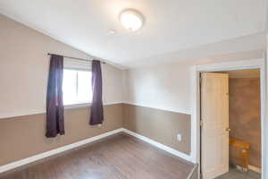 Spare room featuring lofted ceiling and wood-type flooring