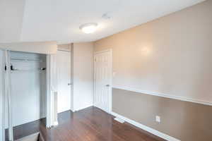 Unfurnished bedroom featuring a closet and dark hardwood / wood-style floors