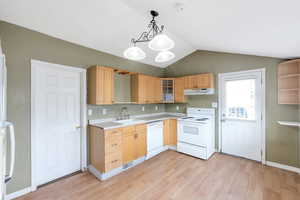 Kitchen with sink, light brown cabinets, white appliances, light hardwood / wood-style floors, and hanging light fixtures