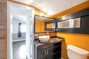 Bathroom with lofted ceiling, vanity, toilet, and hardwood / wood-style floors