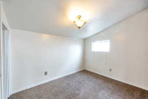 Empty room featuring lofted ceiling and carpet flooring