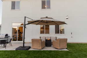 Back of house with large cement patio and lawn. Grill, table and chairs can be INCLUDED. The umbrella, couches and firepit are EXCLUDED.