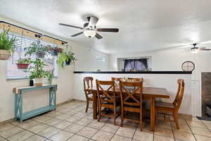 Tiled dining room featuring a textured ceiling and ceiling fan