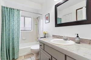 Full bathroom with toilet, tile patterned flooring, shower / bath combination with curtain, and vanity