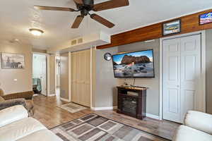 Living room featuring a textured ceiling, ceiling fan, and hardwood / wood-style flooring