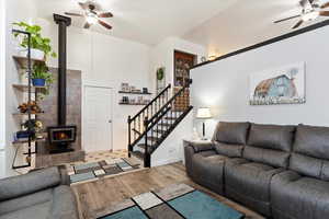 Living room with hardwood / wood-style flooring, ceiling fan, and a wood stove