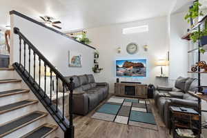 Living room with light wood-type flooring, ceiling fan, and a wealth of natural light