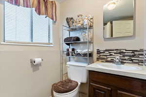 Bathroom with vanity, decorative backsplash, and toilet