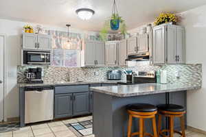 Kitchen with sink, gray cabinetry, kitchen peninsula, and appliances with stainless steel finishes