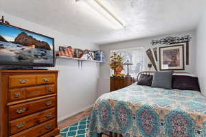 Bedroom with a textured ceiling and wood-type flooring