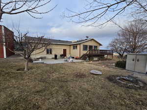 Back of house with a patio area, a lawn, a shed, and a wooden deck