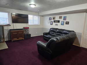 Living room with a textured ceiling and dark colored carpet