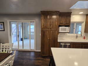 Kitchen featuring sink, dark hardwood / wood-style floors, stainless steel dishwasher, and tasteful backsplash