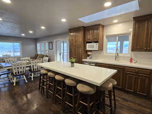 Kitchen featuring sink, a kitchen breakfast bar, tasteful backsplash, a kitchen island, and dark wood-type flooring