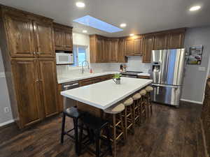 Kitchen with sink, a kitchen bar, a skylight, a kitchen island, and appliances with stainless steel finishes