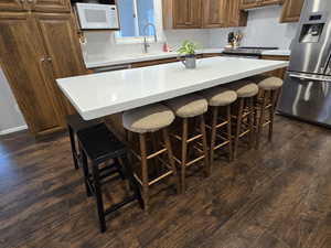 Kitchen with dark hardwood / wood-style floors, a center island, stainless steel fridge with ice dispenser, decorative backsplash, and sink