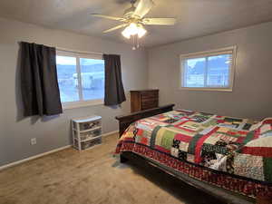 Bedroom with ceiling fan, carpet floors, and a textured ceiling