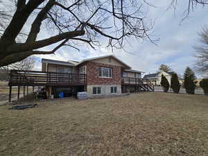 Back of house with a lawn and a wooden deck