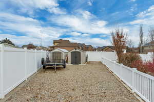 View of side yard featuring 2 storage sheds and RV parking