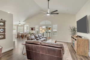 Living room featuring ceiling fan, dark wood-type flooring, and vaulted ceiling