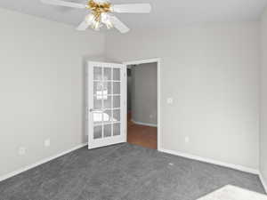 Spare room with french doors, ceiling fan, and dark colored carpet