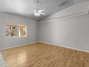 Spare room featuring lofted ceiling, a textured ceiling, ceiling fan, and light hardwood / wood-style flooring