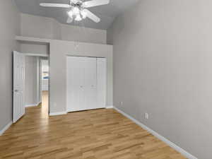 Unfurnished bedroom featuring ceiling fan, light wood-type flooring, a closet, and lofted ceiling